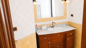 A bathroom with a marble sink, wooden vanity, and a large mirror. - The City Gateway: Cozy Stay in Torino (Torino)
