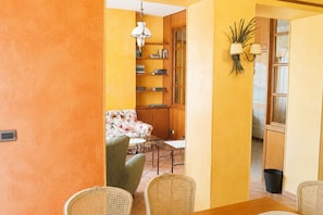A room with a dining table, chairs, a sofa, a bookshelf, and a lamp. - The City Gateway: Cozy Stay in Torino (Torino)