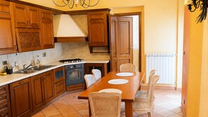 A kitchen with wooden cabinets, a stove, an oven, and a dining table with chairs. - The City Gateway: Cozy Stay in Torino (Torino)