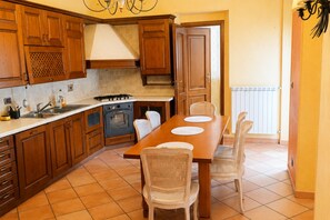 Une cuisine avec des meubles de rangement en bois, une cuisinière, un four et une table à manger avec des chaises.