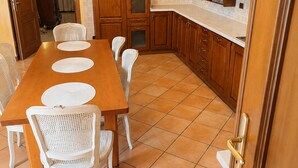 A dining area with a wooden table and white chairs, surrounded by wooden cabinets and a white countertop. - The City Gateway: Cozy Stay in Torino (Torino)