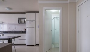 A kitchen with white cabinets, a microwave, a refrigerator, and a glass door leading to a bathroom. - Studio 2min From Beach BC Close to Attrac. Eac1304 (Balneário Camboriú)