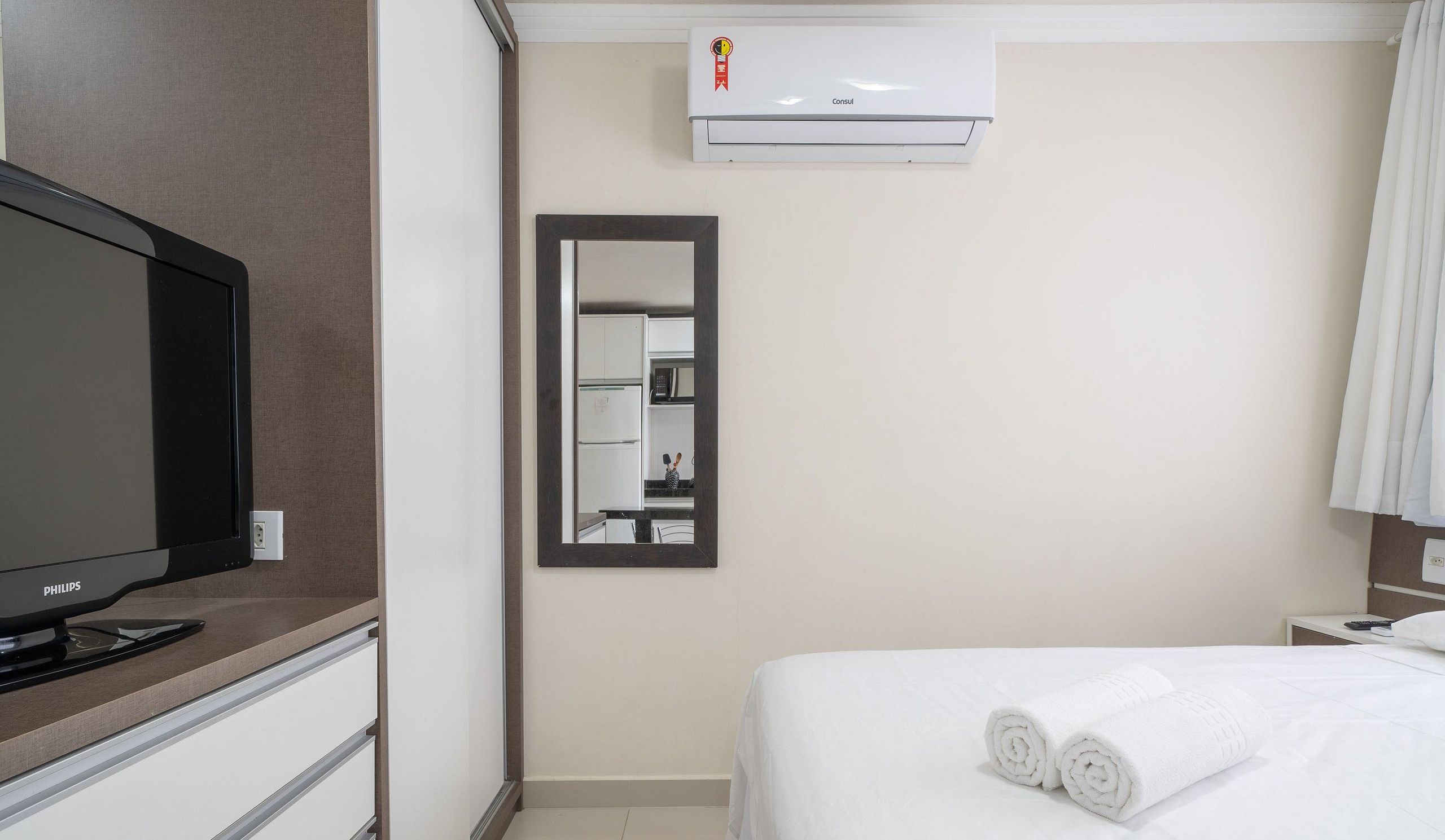 Ein Hotelzimmer mit Bett, Fernseher, Spiegel und Klimaanlage.