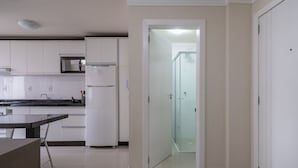 Una cocina con gabinetes blancos, microondas y refrigerador.
