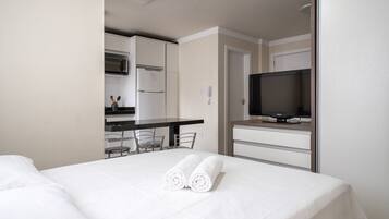 A hotel room with a bed, a TV, a kitchenette, and a dining area.