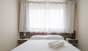 A hotel room with a large bed, two bedside tables, a remote control, and a rolled towel on the bed. - Studio 2min From Beach BC Close to Attrac. Eac1304 (Balneário Camboriú)