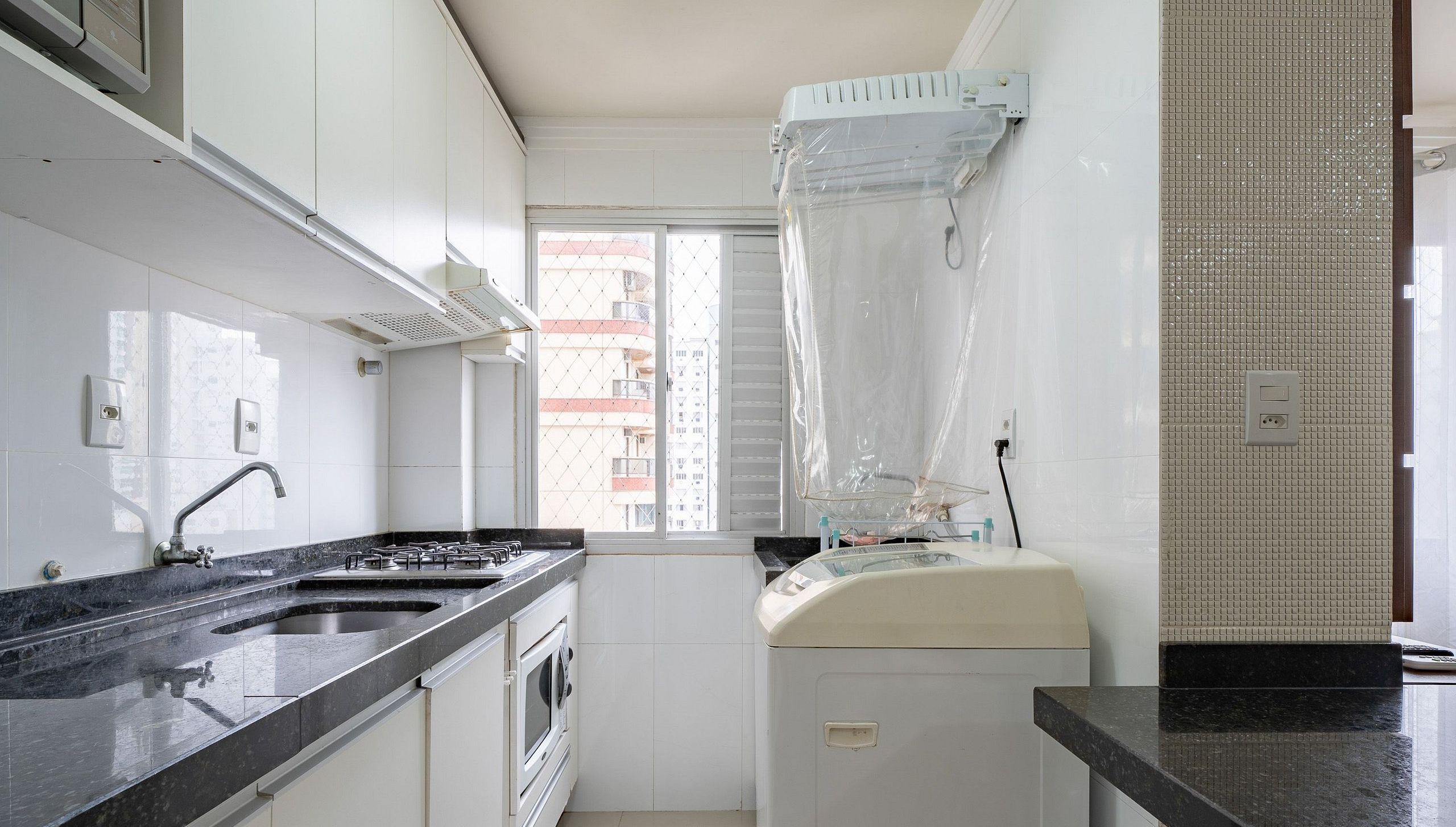 Uma cozinha compacta com uma pia dupla, fogão e micro-ondas.