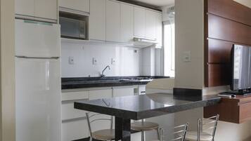 A modern kitchen with white cabinets, a black countertop, and a built-in TV.