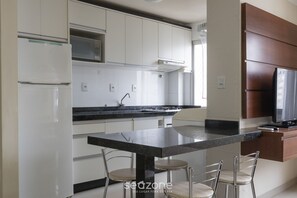 Een moderne keuken met witte kasten, een zwart aanrecht en een ingebouwde televisie.