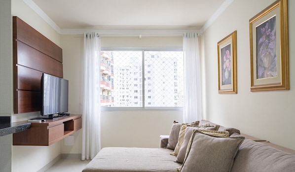 A modern living room with a flat-screen TV, a sofa, and a window with curtains. - Apt 130m From Beach Balneario Camboriu-sc Eac1303 (Balneário Camboriú)