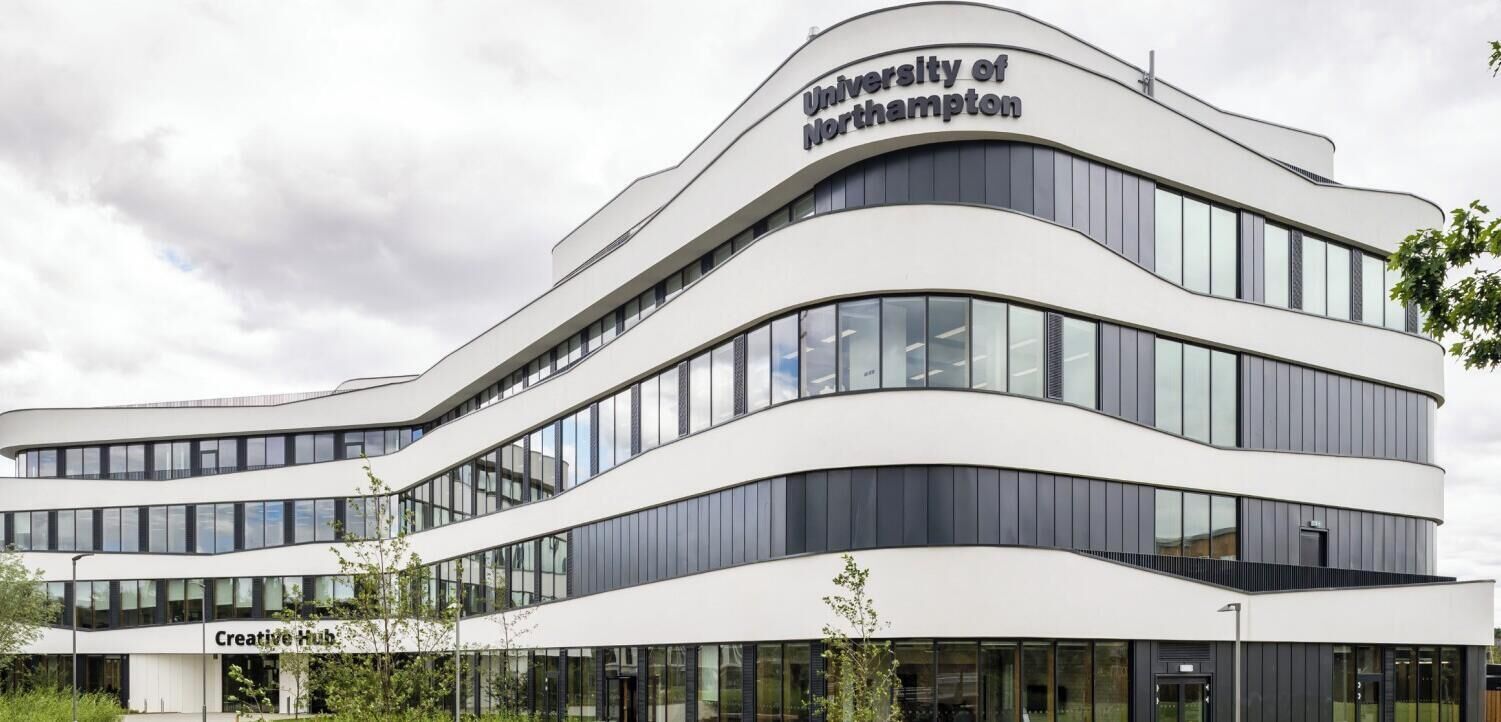 A modern building with the 'University of Northampton' sign, featuring a curved facade and multiple windows.