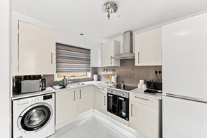 A modern kitchen with a washing machine, oven, and built-in microwave. - Arbour House • Sleeps 5 • Free Parking • Spacious Garden • Fast Wifi • Self-Check-In • Yoko Property (Northampton)