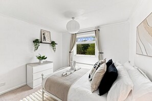 A bedroom with a bed, bedside table, and a window with curtains. - Arbour House • Sleeps 5 • Free Parking • Spacious Garden • Fast Wifi • Self-Check-In • Yoko Property (Northampton)