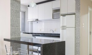 Une cuisine moderne avec des armoires blanches, un comptoir noir et un four à micro-ondes encastré.