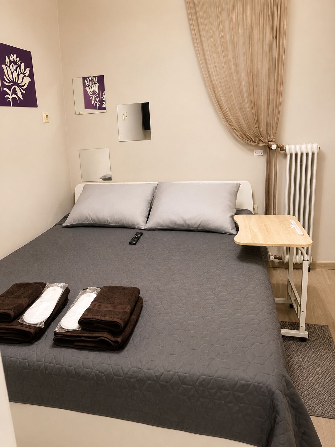 Une chambre d’hôtel avec un lit, une table de chevet, un radiateur et un miroir fixé au mur.