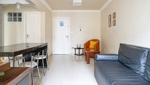 Una sala de estar moderna con un sofá, un comedor con sillas, una encimera de cocina y una puerta con un aviso.