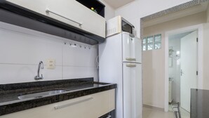 Una cocina moderna con horno empotrado, un lavamanos de acero inoxidable y un microondas.