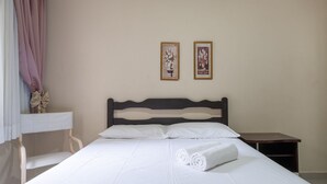 Una habitación de hotel con una cama, una mesita de noche, una silla y dos cuadros enmarcados con motivos florales en la pared.