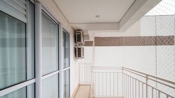 Un balcón con baranda blanca, puerta de vidrio y pared con diseño geométrico de azulejos.