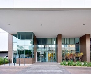 A modern building with a glass facade, a brick base, and a flat roof. - Flat w/ Pool in Setor Bueno - Dnag1701 (Goiânia)