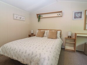 Ein Schlafzimmer mit einem Bett, Nachttischen, einem Regal mit Pflanzen und gerahmten Kunstwerken an den Wänden.