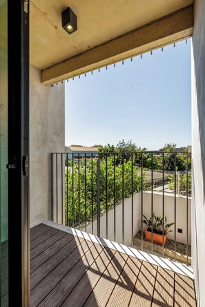A balcony with a wooden floor, metal railing, and a view of greenery and buildings. - Marina da Afurada Apartments - Agatha Christie (Vila Nova de Gaia)