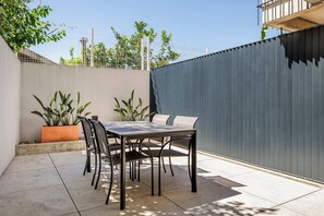 An outdoor patio area with a table and chairs, surrounded by a low wall and potted plants. - Waterfront Studio Apt Near Beach & Dining (Vila Nova de Gaia)