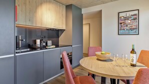 A modern kitchen with grey cabinets, a wooden countertop, and a dining area with a round table and orange chairs. - Marina da Afurada Apartments - Fernando Pessoa (Vila Nova de Gaia)