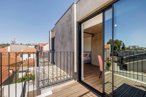 Un appartement moderne doté d’un balcon, de planchers en bois et d’une grande porte vitrée donnant sur une chambre.