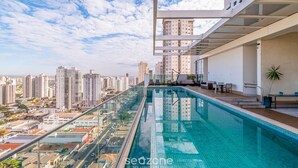 Piscina infinita no terraço com vista para a cidade, arquitetura moderna e área de estar ao ar livre.