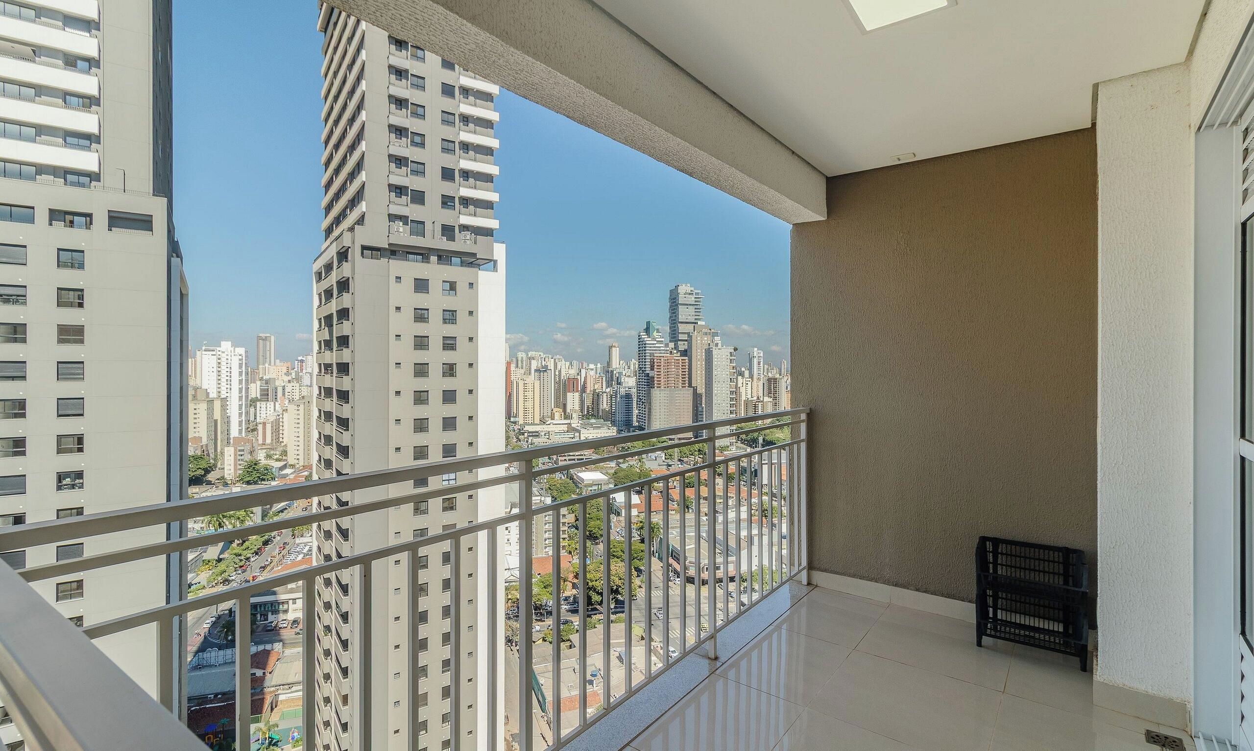 A balcony with a city view, metal railing, and a black crate.
