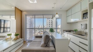 Uma cozinha moderna com ilha embutida, área de refeições com sofá e uma janela grande com vista para a cidade.