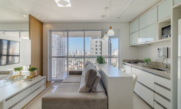 Una cocina moderna con isla integrada, un área de comedor con sofá y un ventanal con vistas a la ciudad.