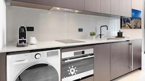 Uma cozinha moderna com máquina de lavar embutida, forno e cafeteira.