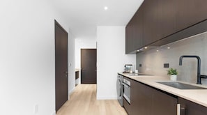 A modern kitchen with dark wood cabinets, a stainless steel sink, and a built-in oven. - Cozy Studio Smart - Miami Downtown (Miami)