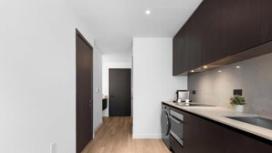 A modern kitchen with dark cabinetry, a stainless steel sink, and a built-in oven. - Design Studio - Miami Pulse E11EVEN (Miami)