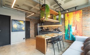 Eine moderne Küche mit Backsteinwand, einem großen abstrakten Gemälde und einem Essbereich mit Holztisch und Stühlen.