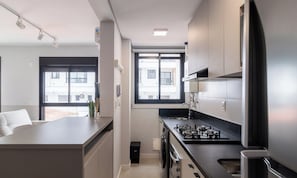 Eine moderne Küche mit Gaskochfeld, Kühlschrank und einem Fenster für natürliches Licht.