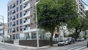 A multi-story residential building with balconies, a gated entrance, and parked cars on the street. - Apt in the Center Close to Beach in Floripa Ech113 (Florianópolis)