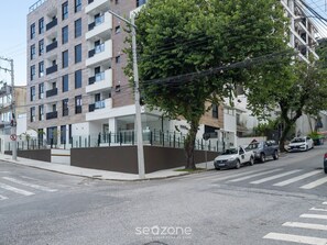 Ein mehrstöckiges Wohngebäude mit Balkonen, einem verschlossenen Eingang und parkenden Autos in der Straße.