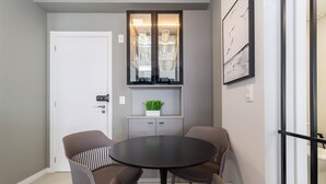 A modern dining area with a round table and four chairs, a cabinet with glass doors, and a framed abstract painting on the wall. - Apt in the Center Close to Beach in Floripa Ech113 (Florianópolis)