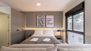 A hotel room with a bed, two bedside tables, a window, and two wall art pieces. - Apt in the Center Close to Beach in Floripa Ech113 (Florianópolis)