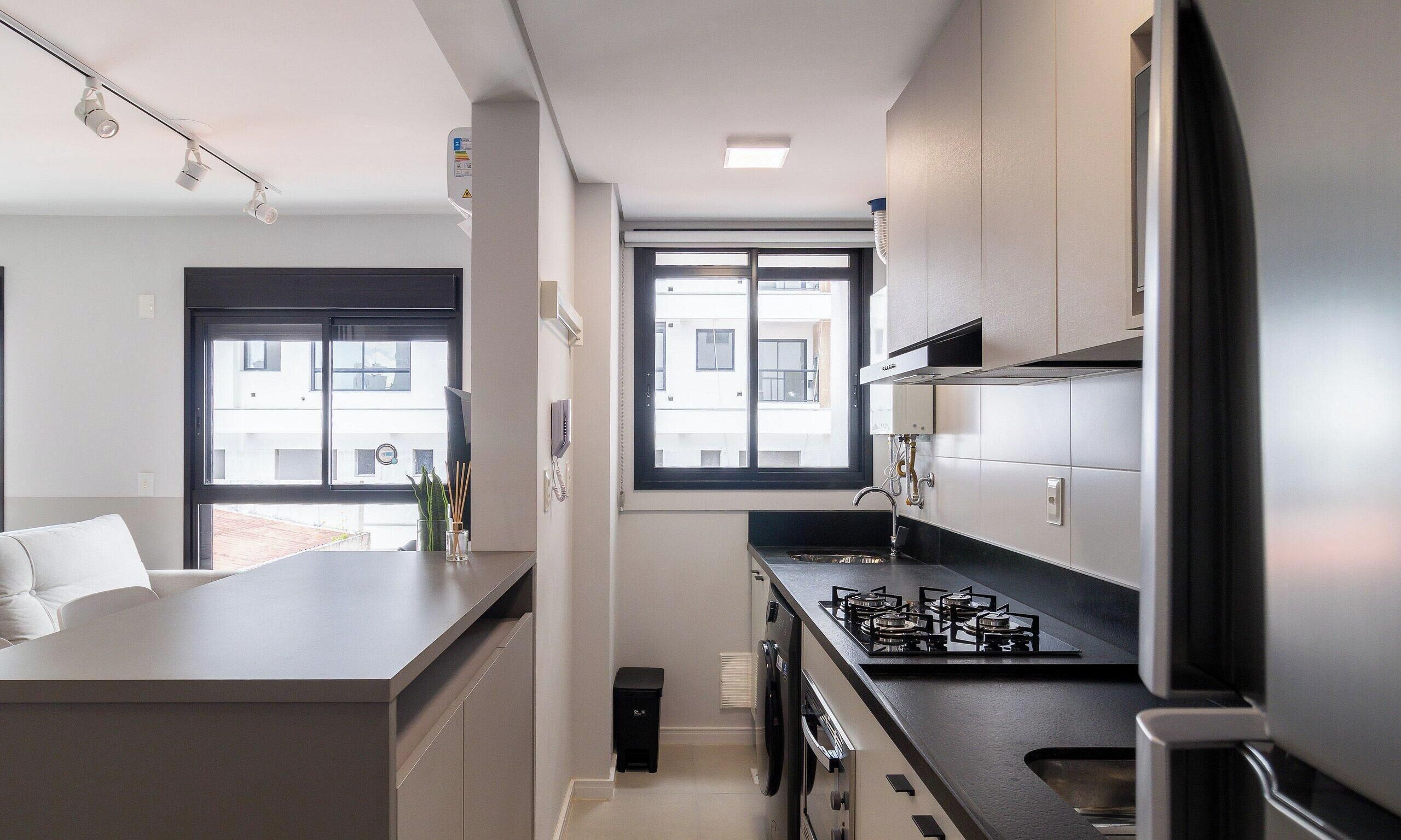 Cocina moderna con estufa a gas, refrigerador y ventana que proporciona luz natural.