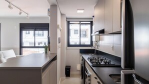 A modern kitchen with a gas stove, a refrigerator, and a window providing natural light. - Apt in the Center Close to Beach in Floripa Ech113 (Florianópolis)