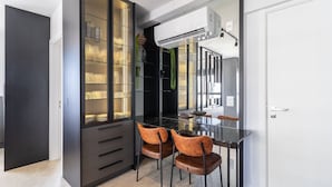 A modern kitchen with a black countertop, two brown chairs, and a glass cabinet with shelves. - Modern Studio in th Center of Florianopolis Ech504 (Florianópolis)