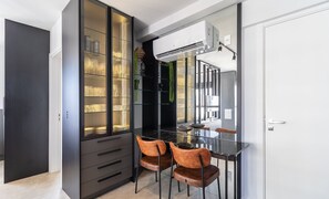 Eine moderne Küche mit schwarzem Arbeitsplatz, zwei braunen Stühlen und einer Glastruhe mit Regalen.