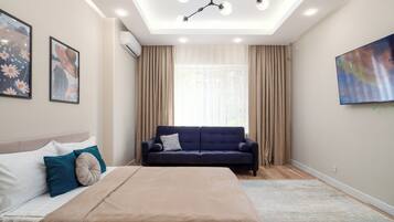 A modern bedroom with a bed, a sofa, and a large painting.