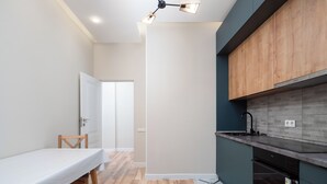 A modern kitchen with wooden cabinets, a black countertop, and a white dining table with chairs. - Comfort 1-room apartments  (Almaty)