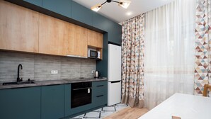 A modern kitchen with a microwave, sink, and dishwasher. There is a dining table with chairs. - Comfort 1-room apartments  (Almaty)