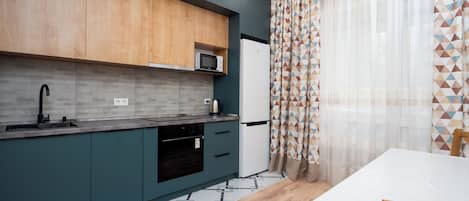 A modern kitchen with a microwave, sink, and dishwasher. There is a dining table with chairs.